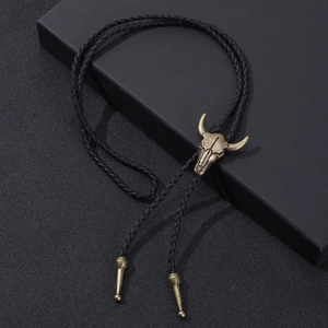 Detail of a vintage bronze bull skull bolo tie on black braided leather cord and gift box