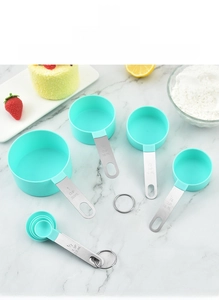 Detail of 5-piece mint green measuring cups and spoons set on marble countertop