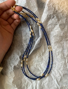 Détail du collier en lapis-lazuli et perles d'eau douce avec fermoir doré sur papier blanc