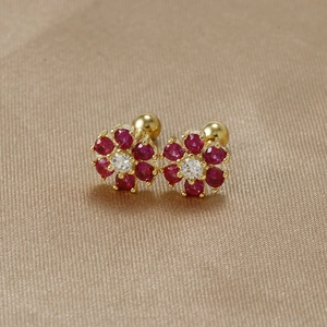 Detail of s925 silver flower earrings with red zircons and screw back on silk