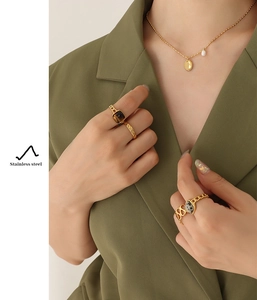 Detail of stainless steel necklace with pearl pendant and gemstone rings on model