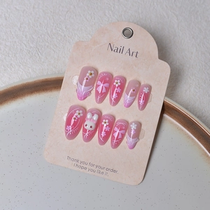 Detailed view of 3D bunny and bow decorations on almond-shaped pink press-on nails