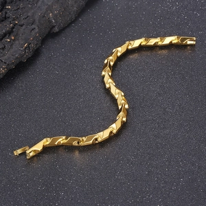 Close-up of golden stainless steel geometric prism link bracelet on dark textured surface