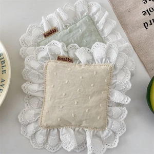 Detail of cotton linen placemats with white lace edges and subtle polka dot textures