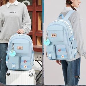 Detail of light blue backpack with multi-pocket design, plush ball, and creative badges