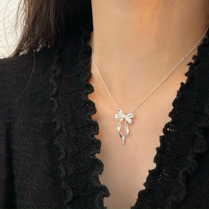 Close-up of S925 sterling silver bow pendant on a delicate chain worn by a model