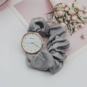 Detail of grey satin scrunchie watch band with silver rhinestones and rose gold dial