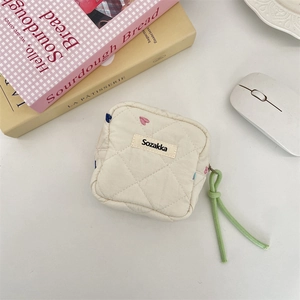 Detailed view of quilted cotton sanitary bag with colorful heart embroidery and green puller