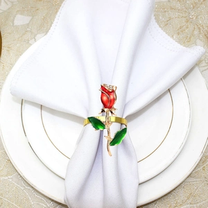 Detail of rose napkin ring with red enamel and rhinestones on a white linen napkin