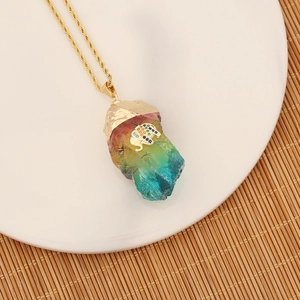 Detail of a natural rainbow crystal pendant with a gold elephant and zircon on a gold chain