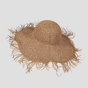 Detail of handmade straw hat with wide brim and long frayed tassel edge for beach sun protection