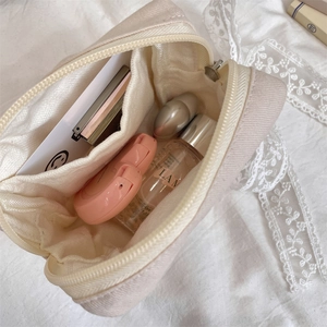 Macro view of cream canvas makeup bag interior with practical multi-layered compartments