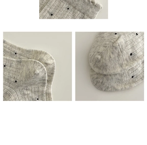 Détail de chaussettes en dentelle grise avec pois noirs et texture tricotée rayée