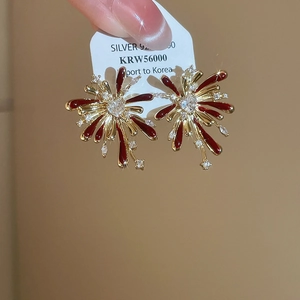 Close-up of gold fireworks earrings with red enamel and heart crystal on silver 925 pins