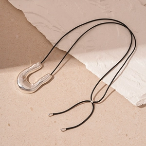Minimalist silver U-shaped geometric pendant necklace with black cord on stone base