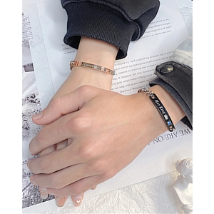 Close-up of His Queen and Her King engraved bracelets on a couple holding hands
