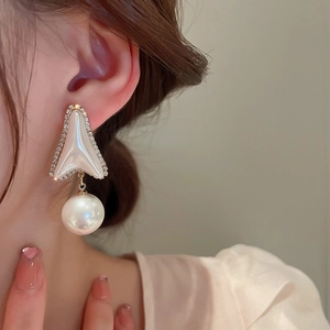 Dettaglio di orecchini con perle, strass e design geometrico a triangolo su modella