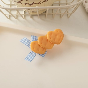 Detail showing heart-shaped biscuit hair clips with blue checkered ribbon on a tray