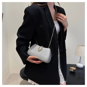 Detail of silver glitter evening clutch with gold oval buckle and metal chain strap