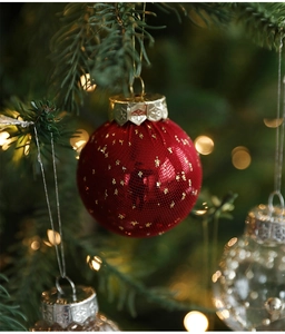 Macro detail of red mesh Christmas ball with gold star glitter on a festive tree