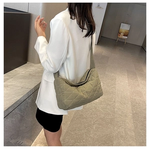 Detail of light green quilted shoulder bag with triangular stitching and wide strap