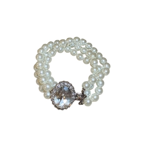 Three-row pearl bracelet featuring a silver-framed oval clear gemstone and sparkling accents