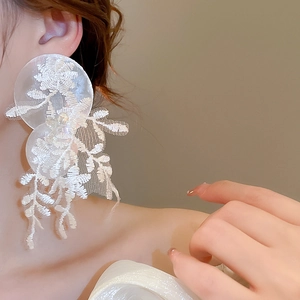 Détail de grandes boucles d'oreilles fleurs en dentelle blanche sur mannequin
