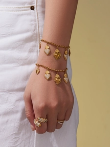 Gros plan de bracelets cœur en acier doré et bagues en diamant sur la main d'un mannequin