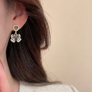 Elegant gold drop earrings with pearl-edged hearts and sparkling rhinestone bows