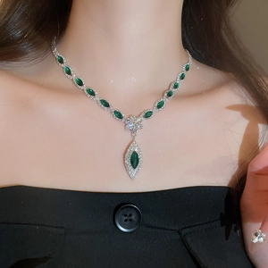 Detailed view of silver necklace with emerald marquise gems and diamonds on model