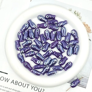 Detailed view of purple ceramic fish beads with evil eye design for DIY jewelry making