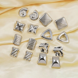 Macro display of assorted geometric silver earrings on silk fabric background