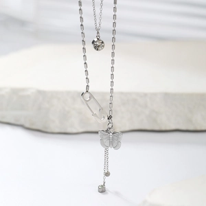 Detail of silver layered necklace with butterfly, paperclip, and zircon tassels