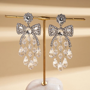 Detail of elegant silver bow earrings featuring shimmering crystal fringe and pear drops