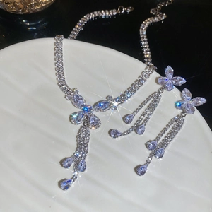 Macro shot of silver butterfly necklace and earrings set with tassel and zircons