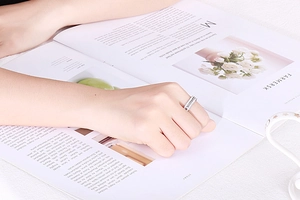 Detailed view of a silver minimalist diamond band ring displayed on a fashion magazine