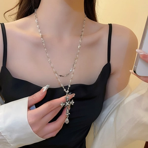 Dettaglio di una collana a doppio strato con ciondolo a croce e zirconi su collo donna