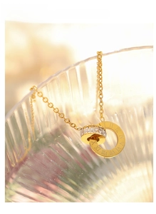 Detail of 18K gold-plated double ring pendant with Roman numerals and clear crystals