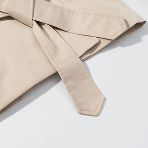 Détail d'une veste beige avec ceinture à nouer et texture de tissu en armure toile