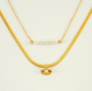 Detail view of double-layered gold necklace with ginkgo leaf pendant and white pearls