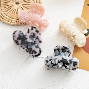 Flat lay of assorted marble and tortoiseshell acetate hair claws on textured white background