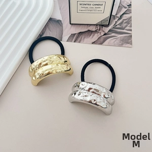 Detail of gold and silver irregular textured metal hair ties on a minimalist background