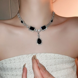 Detailed view of silver necklace with black geometric rhinestones and a teardrop pendant