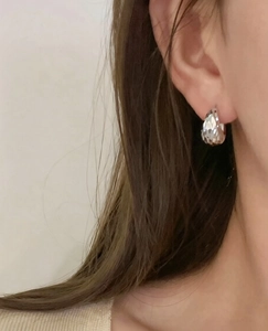 Close-up of water-drop silver earrings with faceted crystals on a model's ear