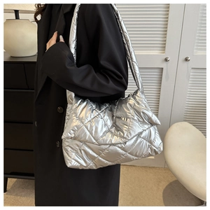Silver quilted shoulder bag with soft padded texture shown on a model side view