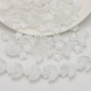 Close-up of translucent matte moon and star beads for DIY jewelry making in a white tray