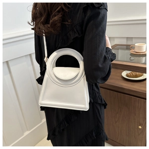 Detail of white PU leather handbag featuring a round handle and elegant stitched edges