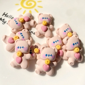 Close-up of pink resin bear charms with yellow bows on a white decorative ceramic plate