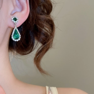 Detail of pear-cut emerald green gemstone earrings with white crystal halo