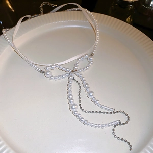 Detail of elegant pearl bow choker with long fringe tassels on white ceramic plate